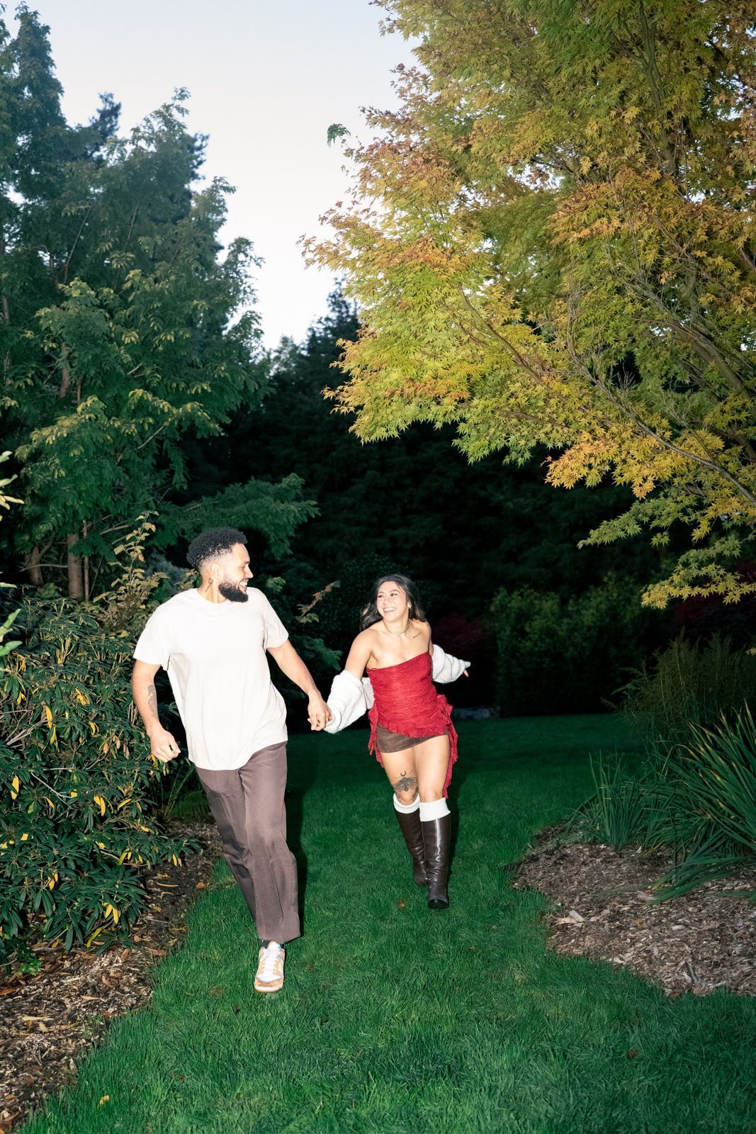 Couple running hand in hand through a garden
